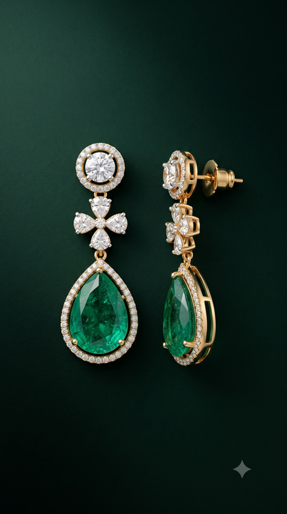 A pair of gold drop earrings featuring large emerald-cut green gemstones and pavé-set clear stones, shown on a dark green background.