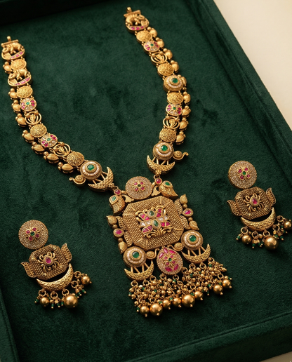 Gold necklace and earrings set on a green velvet background